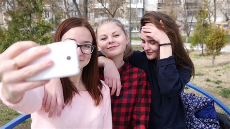 Cute Teen Girls Take Fun Selfies Together At Beach Stock