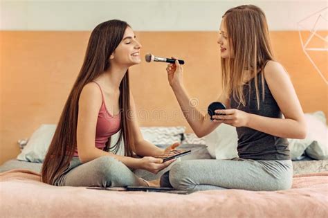 pleasant teenage girls training in applying makeup stock