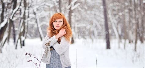 winter portrait of a cute redhead lady in grey coat and scarf walking