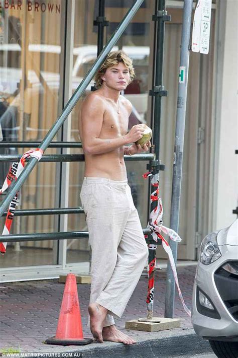 jordan barrett shirtless and barefoot as he drinks coconut water in