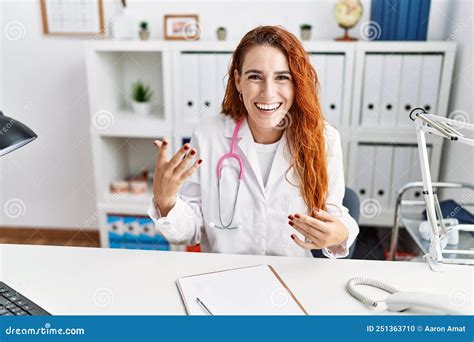 Young Redhead Woman Wearing Doctor Uniform Speaking At Hospital Stock