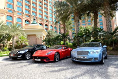 luxury cars parked  front   large building  palm trees