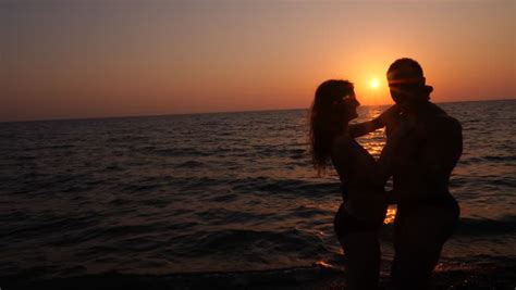 Loving Teen Couple Sitting On The Beach At Sunset