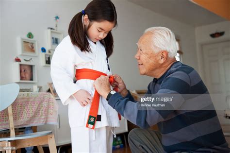 Japanese Grandfather Helping Granddaughter With Karate Uniform High Res
