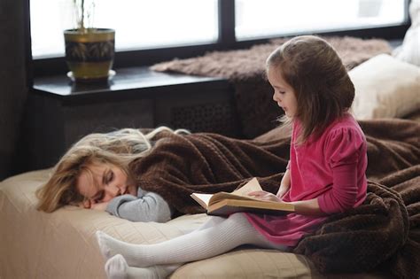 Premium Photo Daughter Reads The Book On The Bed While Mom Sleeps