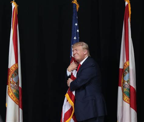 trump awkwardly hugs  flag  defending immigration policies