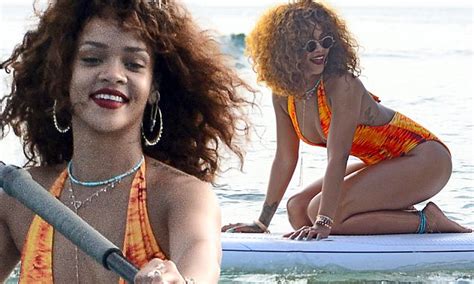 rihanna showcases her curves in a flame coloured swimsuit