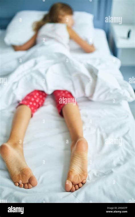 girl s feet covered with white bed sheet sleeping in a comfortable bed
