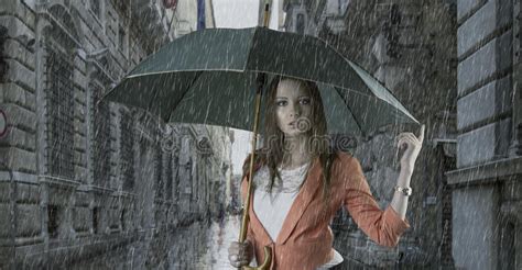 beautiful woman with umbrella in town under rain stock