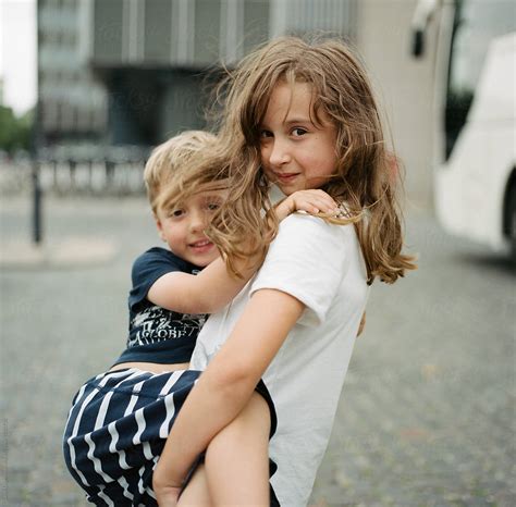 big sister carrying her little brother by stocksy contributor jakob