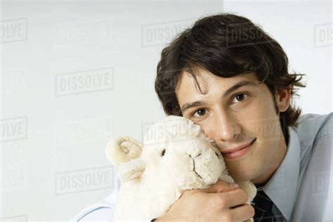 young man holding stuffed toy  cheek smiling  camera stock