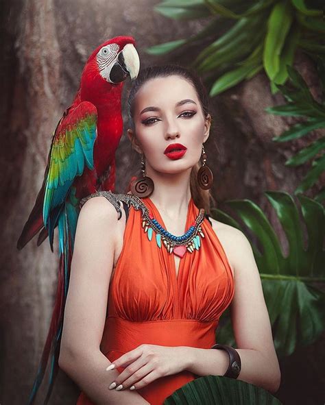 A Beautiful Woman In An Orange Dress With A Parrot On Her Shoulder And