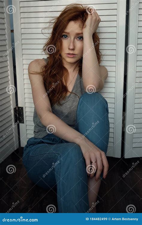 Redhead Girl With Freckles In A Gray T Shirt Is Looking At The Camera