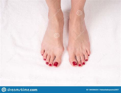 female slim bare feet on white terry towel close up red