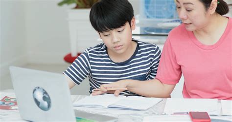 serious asian mother with son doing homework in the living