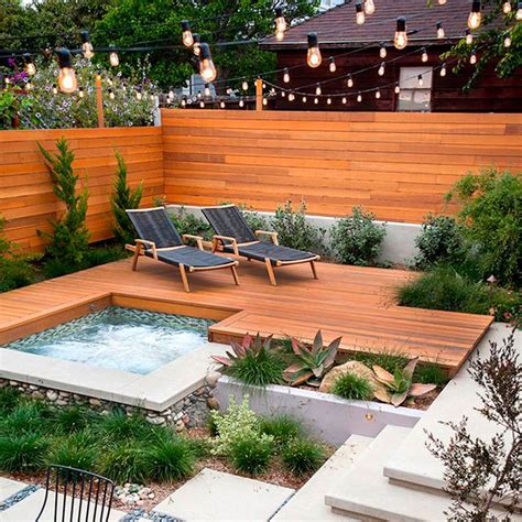 An Outdoor Hot Tub In The Middle Of A Wooden Deck With Lights Strung
