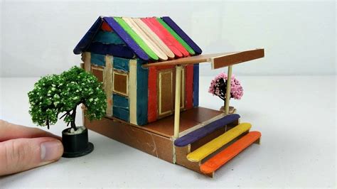 hand  holding  miniature house    wood  painted rainbow colors   small