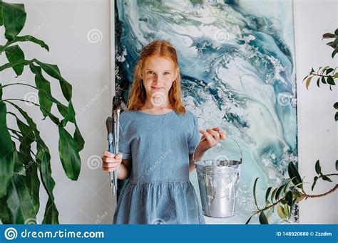 portrait of shy teenage redhead girl with bunch of brushes in hand