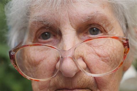 Old Woman In Glasses Looking Into Camera Outdoor Portrait