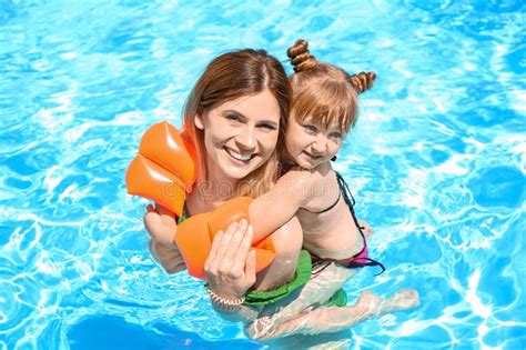 mother hugging daughter in swimming pool stock image
