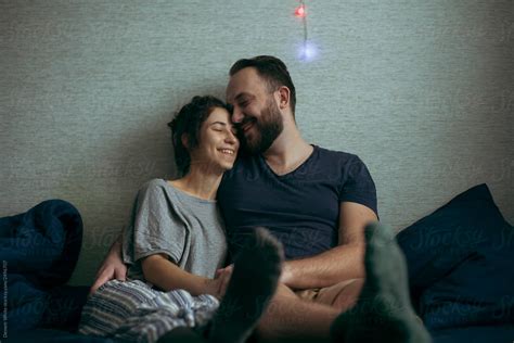 husband and wife are smiling and laughing hugging on the couch by