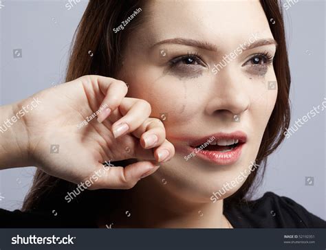 portrait of beautiful crying girl with smeared mascara drying her tears