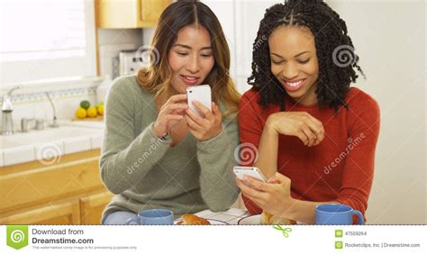 African American And Asian Friends Using Mobile Phones And