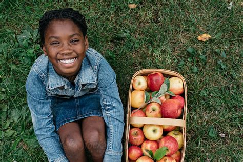 smiling african american girl next to a basket of apples by gabriel