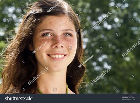 a lovely smiling freckled faced teenage girl with sunlit hair gazes off into the distance stock