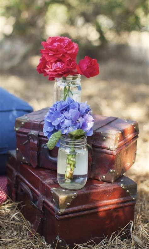 Flowers In A Mason Jar Sitting On Top Of An Old Trunk With Other Suitcases