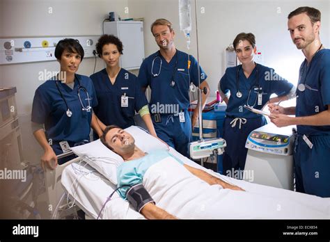 team  doctors standing  smiling patient lying  bed  intensive care unit stock photo