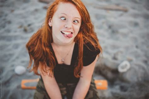 portrait of redhead teenage girl sitting at the beach being goof del