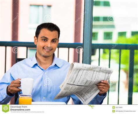 handsome man eating breakfast and reading newspaper stock