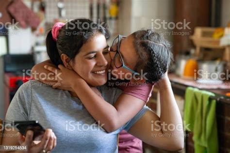 loving girl kissing her mother while shes checking her cell phone at