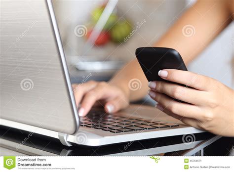 woman hand using a smart phone and typing a laptop at home