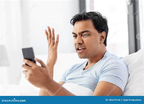 angry indian man  smartphone  bed  home stock photo image