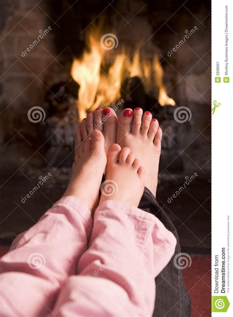 mother and daughter s feet warming at a fireplace stock