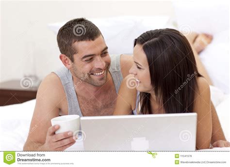 husband and wife in bed using a laptop royalty free stock