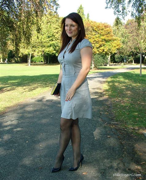 clothed woman shows off her nylon ensconced legs and pumps in the park