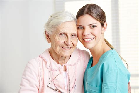 smiling caregiver embracing happy senior woman  nursing home lpn