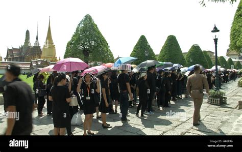 thai people wait in line in the grand palace to pay respects to the
