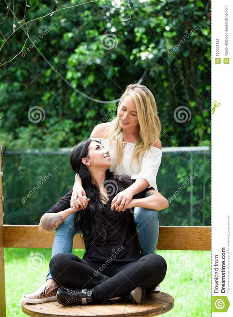 a pair of proud lesbian in outdoors sitting on a wooden table blonde