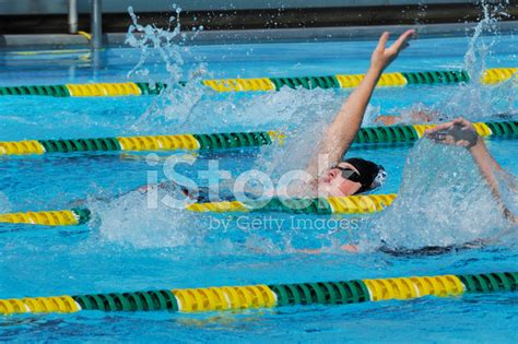 teenage male backstroke swimmer racing  pool stock