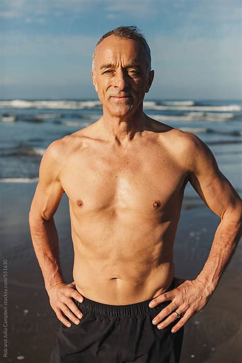 Active Senior Man In Great Shape Standing Shirtless On Beach In