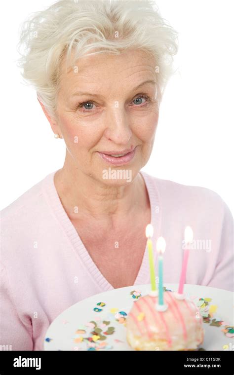 A Mature Woman Holding A Plate With A Donut With Candles In Her Hands