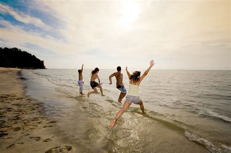 group of friends jumping into the sea stock images image