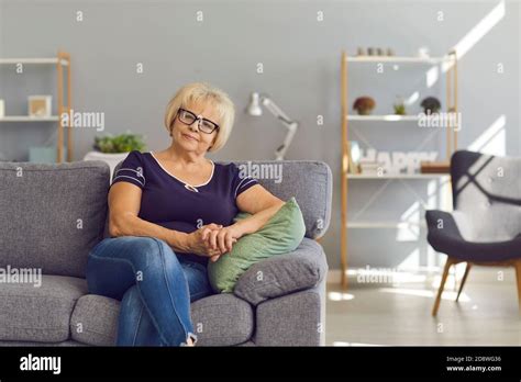 Mature Woman Sitting On Comfortable Sofa In Her Modern Living Room And