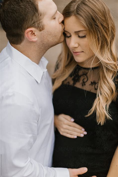 husband kissing  pregnant wife   forehead  stocksy contributor kristen curette