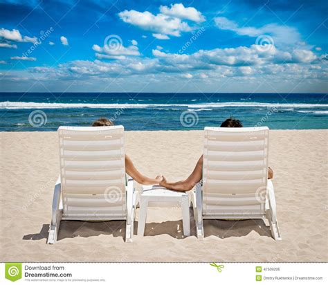 Couple In Beach Chairs Holding Hands Near Ocean Stock