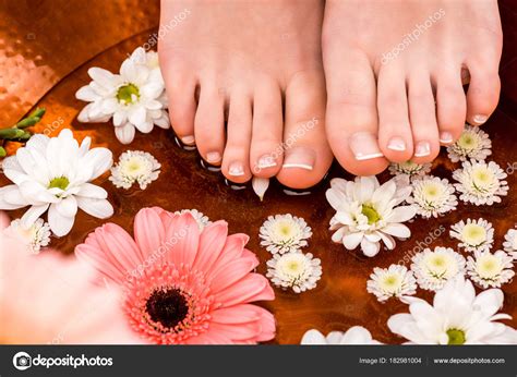 cropped view woman making spa procedure flowers feet stock photo